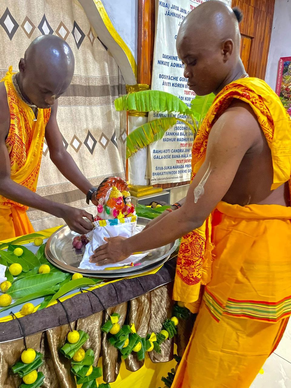 Devotees performing Abhishek ceremony, bathing the deity of Sri Sri Laxmi Nrsimhadeva at ISKCON Kumasi.
